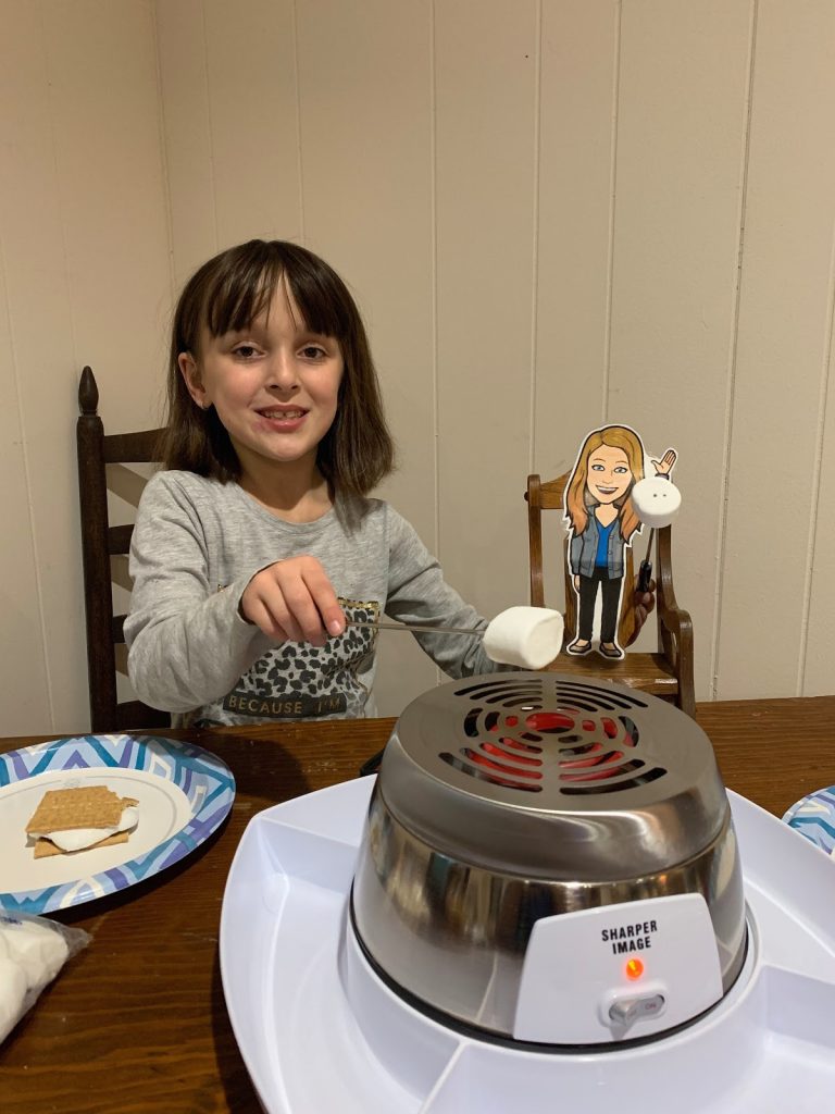 A girl is sitting at the table with a sandwich on it.